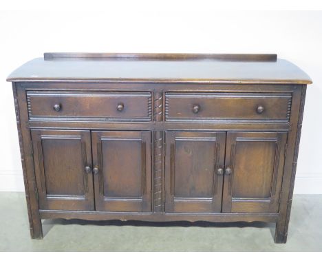 An Ercol sideboard of two drawers above four doors raised on square supports - 144cm x 50cm x 92cm high