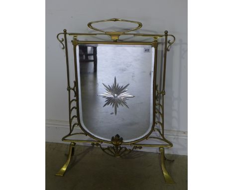 A brass and mirror fire screen of shield shape