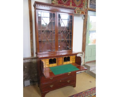 An early 19th century mahogany secretaire bookcase with two astragal glazed doors over a secretaire drawer enclosing a fitted