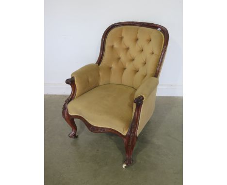 A Victorian carved walnut button back armchair with scroll arms and cabriole legs