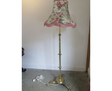A telescopic brass standard lamp on a triform base