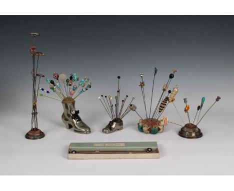 Five pin cushions together with seventy-three vintage and antique hat pins, comprising two novelty white metal pin cushions i