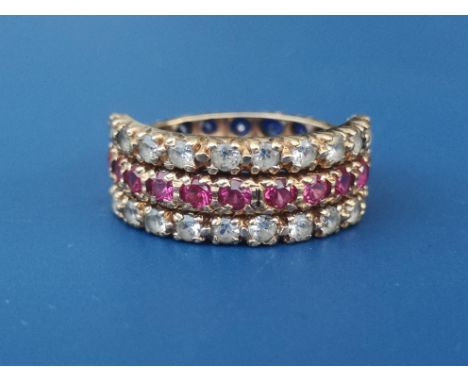 A day &amp; night eternity ring having hinged outer sections, set with red, white &amp; blue stones in yellow metal.  Finger 