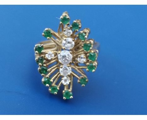 A 1960's emerald &amp; diamond Brutalist style cluster ring, seven claw set brilliant cut diamonds arranged in an offset cros