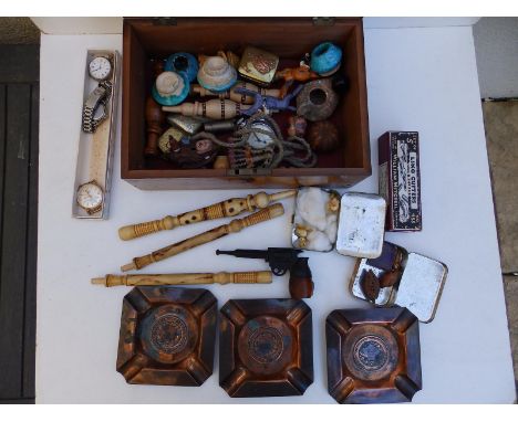 A wooden box containing an Eiffel Tower souvenir pipe in the form of a revolver and other collectors' items.