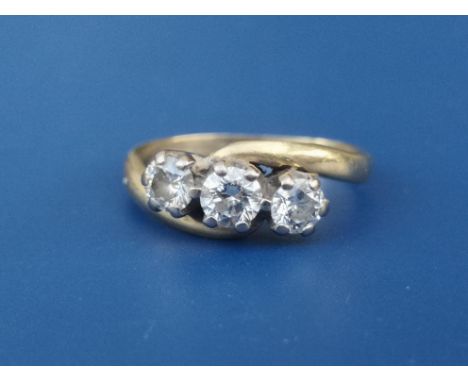 A three stone crossover set diamond ring, the claw set stones of total weight approximately 0.75 carat, on 18ct gold shank.  