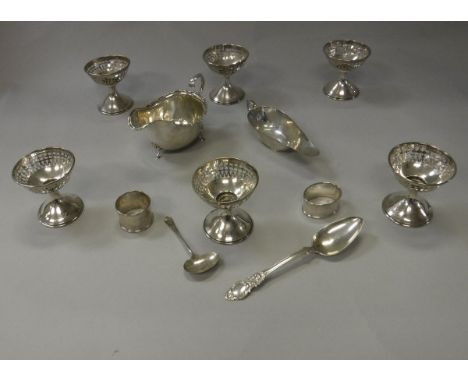 A collection of small silver wares to include two sauce boats, sauce ladle, dessert spoon, six sterling silver pedestal salts