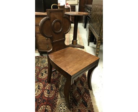 A pair of early 19th Century mahogany panel seated hall chairs with brass handles to the top rail raised on sabre supports CO