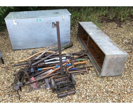 A large Acorn galvanised lidded feed bin together with a galvanised feeding trough and assorted garden hand tools