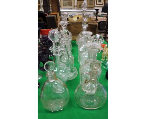 A collection of twelve decanters and ewers including one etched with insects playing billiards, a star cut spirit flagon insc