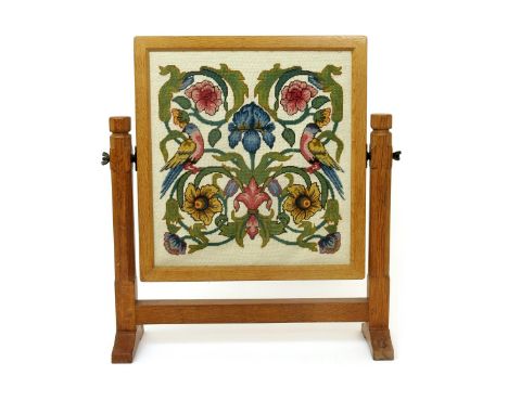 A Robert Mouseman Thompson oak firescreen, with embroidered panel, the reticulated rectangular panel on carved frame, with ca