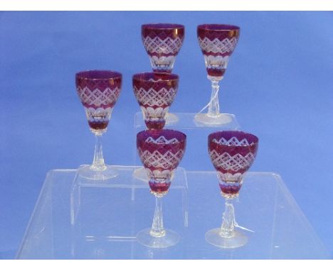 A set of six continental ruby-flashed Wine Glasses, each with a bell-shaped bowl cut with hobnails and flutes, on clear reede