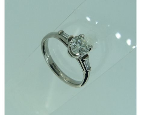 A single stone Diamond Ring, with a baguette diamond on each shoulder, the central circular cut stone, c.¾ct., all mounted in