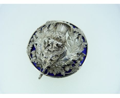 A large white metal and blue enamel Plaid Brooch, the open centre set with a large thistle and leaves and with smaller thistl