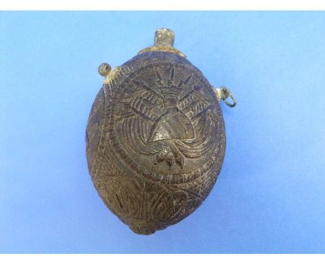 An Early 19th Century Carved Coconut Bugbear Powder Flask, the body carved in relief with military and musical trophies, mili