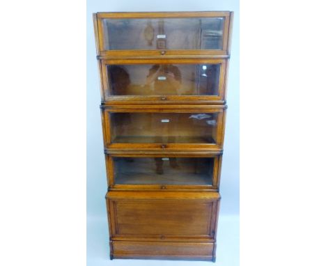 A Globe Wernicke oak bookcase, with four graduated glass fronted tiers on cupboard with fielded panel door and shaped platfor