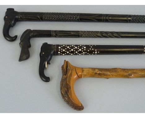 A walking stick, the hardwood handle carved as a crocodile, 90cm long, two Indian ebony walking sticks each with carved eleph