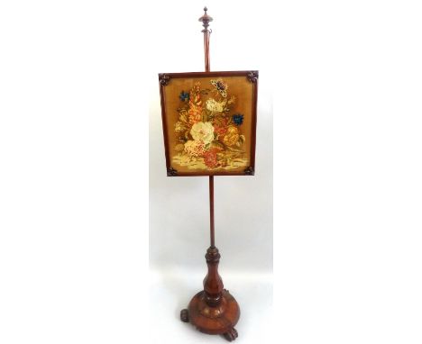 An early Victorian mahogany pole screen, with turned finial, rise and fall framed and glazed oblong needlework panel on plain