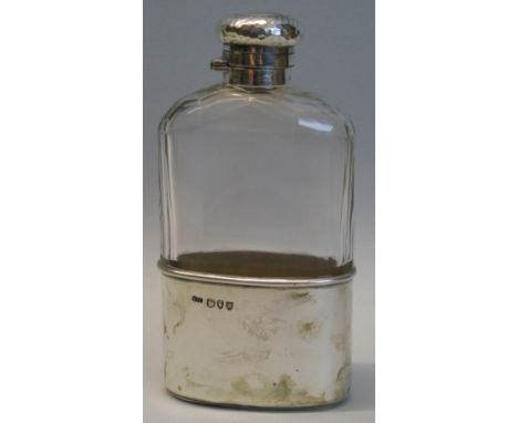 A Victorian spirit flask, the faceted clear glass bottle with beaten screw top and removable beaker/half cover with silver gi