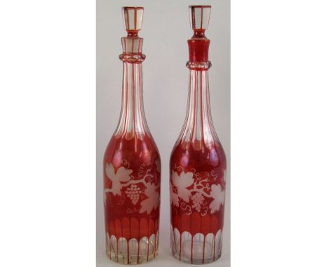 A pair of ruby flashed decanters, of bottle shaped form, each with slice cut neck and base, fruiting vine etched body and tap