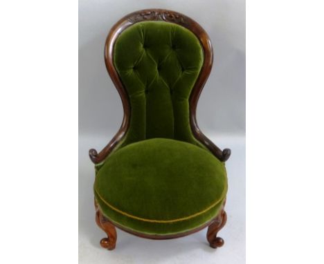 A Victorian walnut framed nursing chair, the waisted button upholstered back with scroll carved crest, upholstered seat and s