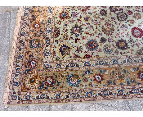 A Persian carpet, the central oblong panel with numerous flowerheads in blue, red, black and orange on an ivory ground within