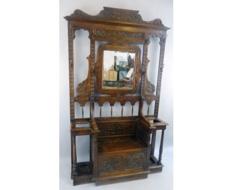 A Victorian oak hall stand, carved all over in the Jacobean style with scrolling pediment and moulded cornice over an open ba