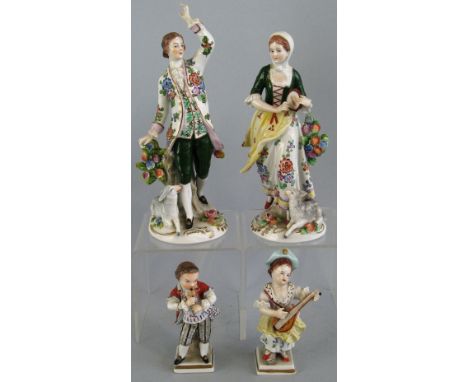 A pair of Sitzendorf figures, of a man and woman in 18th Century costume, he standing beside a floral encrusted tree trunk wi