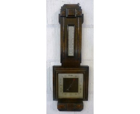 An early 20th Century oak cased aneroid barometer, in the Art Deco style of angular form with applied carvings, the stepped p