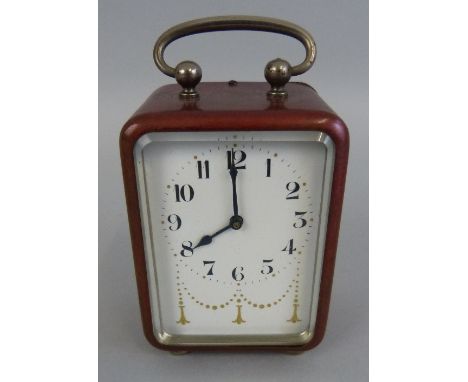 An early 20th Century travel alarm clock, in the form of a red tinted brass carriage clock, the gilt decorated enamel dial wi