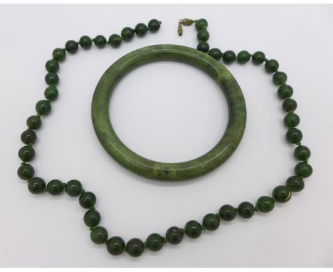 A jade bangle, a/f and a bead necklet, fastener requires repair