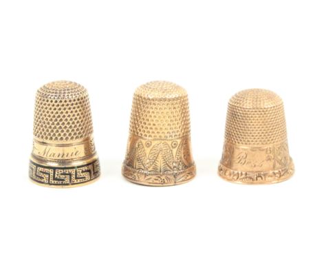 Three American gold thimbles comprising an example with decorated border and dated, 1873, another engraved with buildings and