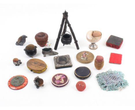 A collection of pin cushions including two bog oak cauldrons, one on tripod, a soft metal parrot, 4cm, a white metal frog exa