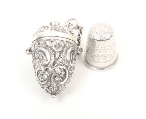 A Victorian silver thimble case with silver thimble, the case of egg form decorated with ïCÍ scrolls and flowers, the hinged 