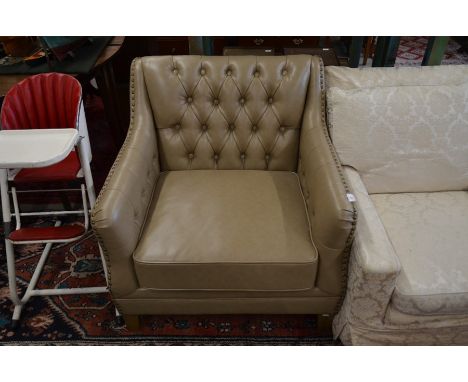 A modern club armchair with mocha brown button back and brass studded leather upholstery, light oak supports