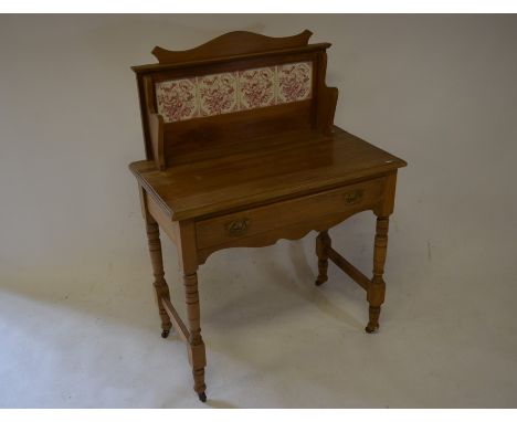 An Edwardian tile backed wash stand with single frieze drawer, turned supports and castors, 85 cm wide