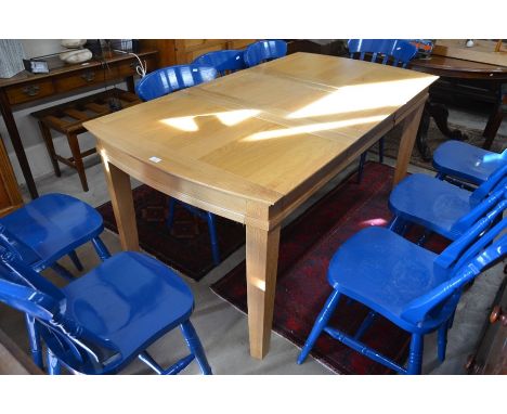 A modern light oak extending dining table with single storable central leaf and cleated rectangular top raised on square supp