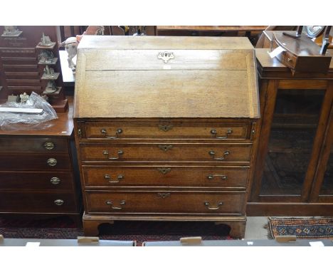 A George III oak fall front bureau with fitted interior and four crossbanded graduating drawers with brass swan-neck handles,