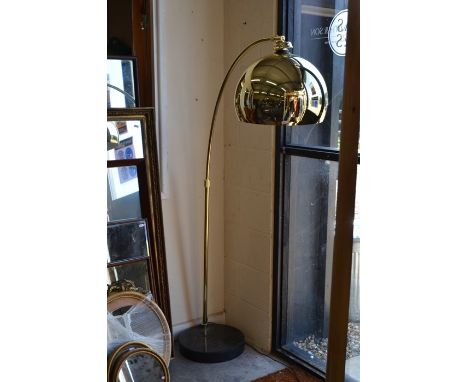 A polished brass-finished Arc floor lamp with weighted circular base