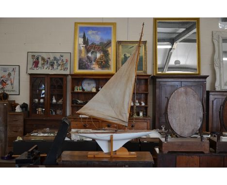 A wooden model of a J-Class pond yacht with mast, beam and sloop rigged with cloth mainsail, painted hull and weighted keel c