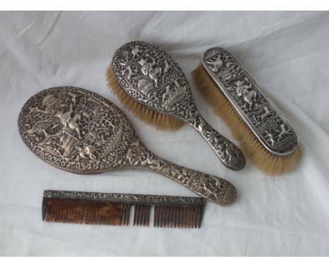 A heavy Eastern silver dressing table set of hand mirror, two  brushes and a comb with chased decoration    
