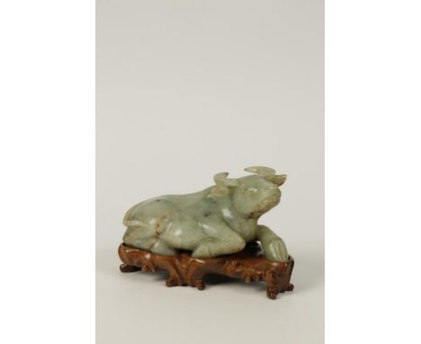 A CHINESE GREEN JADE WATER BUFFALO, the recumbent animal with its' head raised and turned to the right, the stone with some r