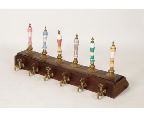 A COLLECTION OF SIX CERAMIC HANDLED BEER PUMPS with brass fittings and brightly coloured ceramic handles, mounted in a line w