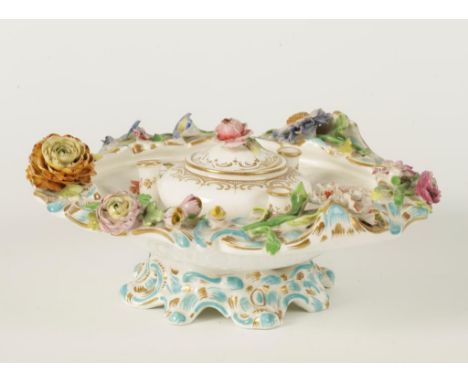 AN ENGLISH PORCELAIN INKWELL painted in polychrome with flowers within a floral encrusted rococo border raised on a spreading