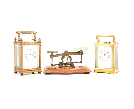 Two brass cased carriage clocks, 16cm and 14cm high; and a set of Edwardian postal scales, width 17.5cm.Condition report:Both