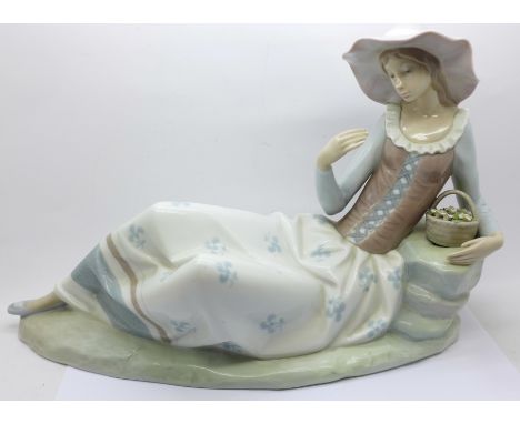 A large Nao figure of a girl reclining, lacking flower from hand 