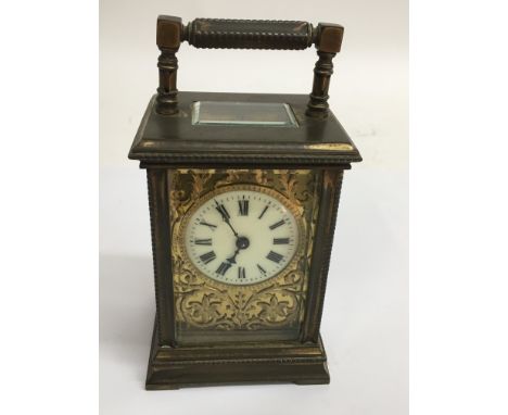 A brass carriage clock with giltwork dial