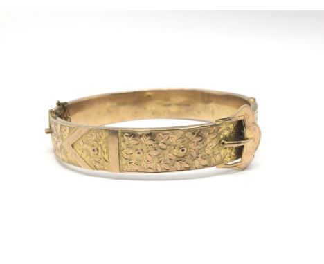 A 9ct gold bangle with floral and buckle decoration. Total weight approximately 13.8 grams.