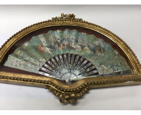 An early 19th century fan with mother of pearl sticks and raised silver foliage the central decoration of courting couples in