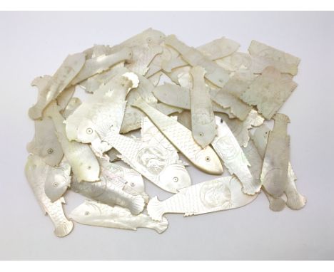 A collection of Chinese mother of pearl counters, mostly in the form of fish.